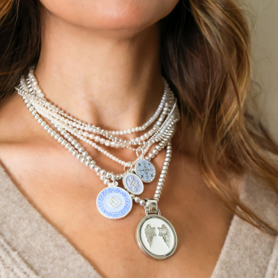 Close up of a woman wearing multiple necklaces with pendants
