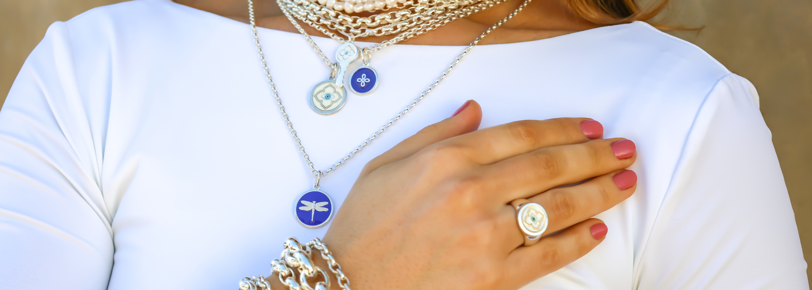 Close-up of a person wearing multiple necklaces, bracelets, and a ring on a white background