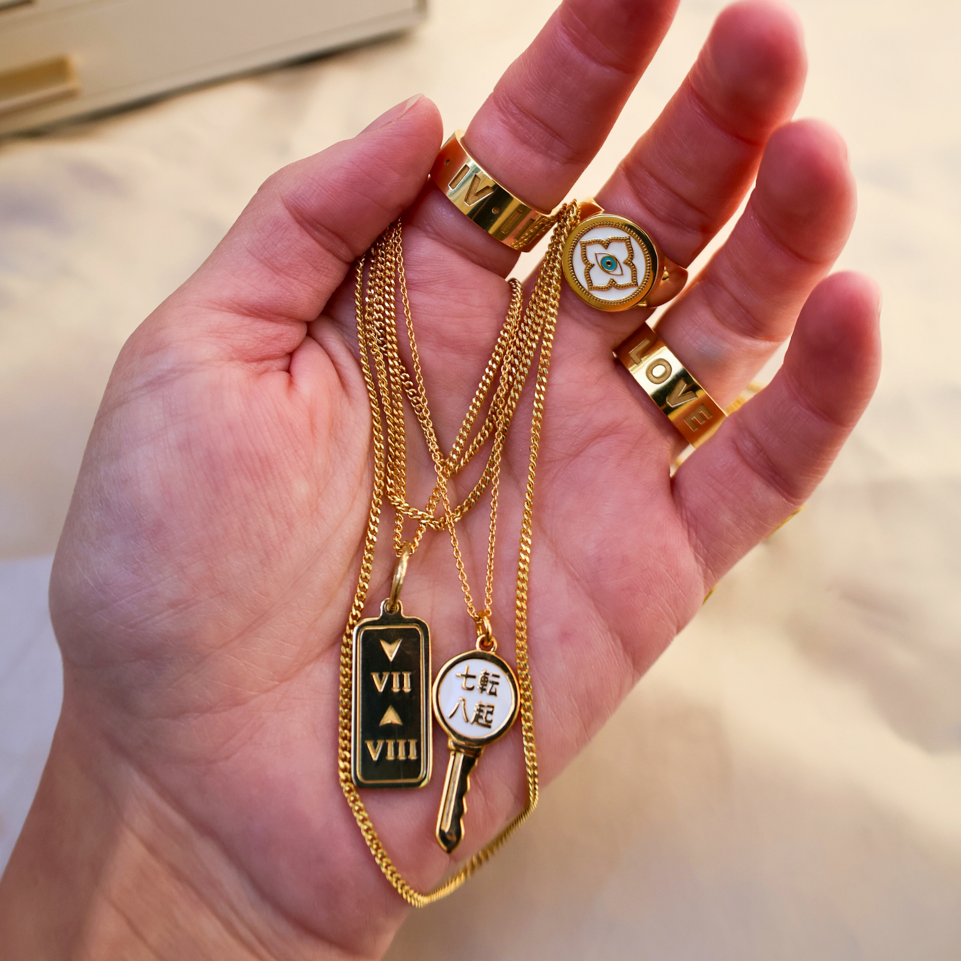 Hand holding gold necklaces with various pendants  - 3